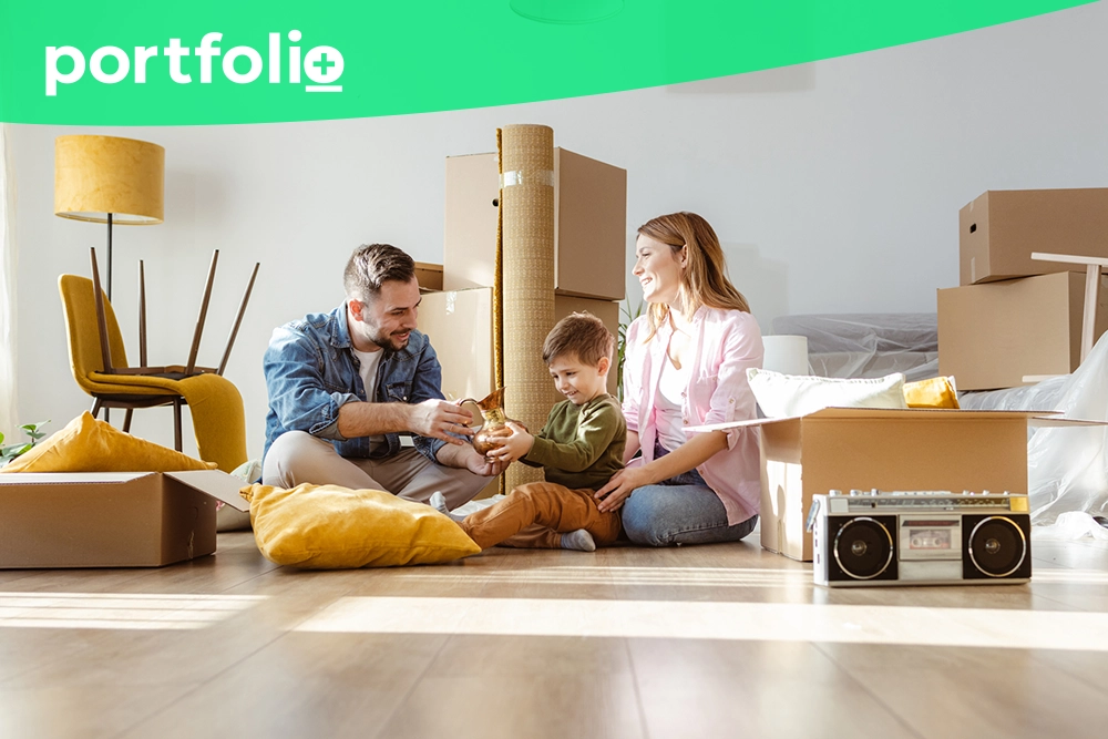 A borrower and her family sitting on the floor of their new home with boxes after receiving mortgage funding through their bank's loan management software.